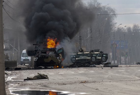 [하르키우=AP/뉴시스] 27일(현지시간) 우크라이나 하르키우에서 러시아군 병력수송 장갑차(왼쪽)가 불타고 있고 그 앞에 생사를 알 수 없는 한 군인이 쓰러져 있다. 2022.02.28.