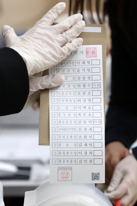 [서울=뉴시스] 백동현 기자 = 제20대 대통령선거 사전투표가 시작된 4일 오전 서울 서초구 반포1동 주민센터에 마련된 사전투표소에서 관계자가 안철수 국민의당 대표와 김동연 전 경제부총리 투표란에 '사퇴' 표시된 투표지를 전달하고 있다. 2022.03.04. livertrent@newsis.com