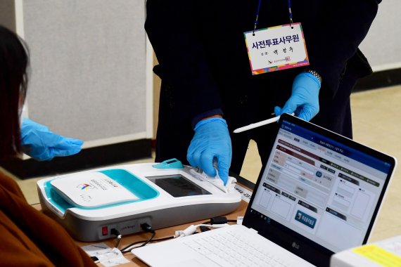 [남해=뉴시스] 차용현 기자 = 제20대 대통령선거 사전투표 첫날인 4일 오전 경남 남해군 남해화전도서관에 마련된 사전투표소에서 사전투표 사무원이 본인확인기를 소독하고 있다. 2022.03.04. con@newsis.com