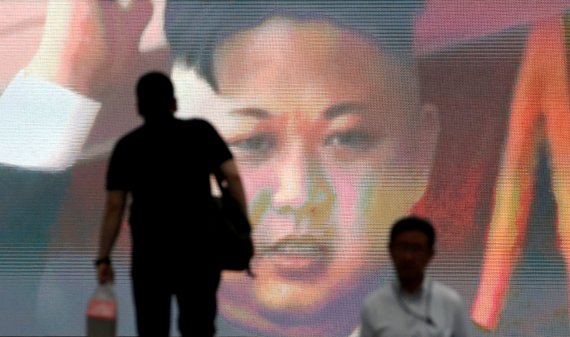 북한 김정은 국무위원장의 이미지 앞으로 두 남성이 걸어가는 장면. 과거 북한이 탄도 마사일을 발사했을 당시, 일본 도쿄의 한 중심가에 마련된 대형 모니터를 통해 김 위원장의 모습이 흘러나오는 순간을 포착한 사진. 로이터 뉴스1