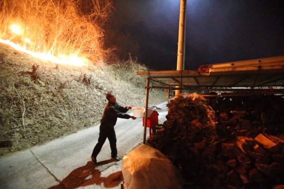 [강릉=뉴시스] 김경목 기자 = 5일 새벽 강원도 강릉시 옥계면 남양리 백봉령 일대 매봉산에서 발생한 산불로 인해 주택 화재가 발생하는 가운데 주민이 장작에 물을 붓고 있다. 2022.03.05. photo31@newsis.com