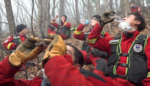 경북 울진군 응봉산 주불을 잡기 위해 헬기 급속로프로 정상에서 투입된 산림청 산림항공본부 공중진화대원들이 12일 오후 진화작업 중 물을 마시며 지친 몸을 잠시나마 쉬고 있다. 특수부대 출신들로 구성된 공중진화대는 헬기 급속로프를 이용 산불 가운데 뛰어들어 방화선을 구축하고 기계화장비 등으로 진화작업을 하는 최정예 진화팀이다.(산림청제공)2022.3.13/뉴스1 © News1 최창호 기자