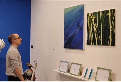 자신의 작품을 감상하고 있는 타일러 라쉬. 전시장에는 그의 저서 '두 번째 지구는 없다'와 그림 '고래 2'(2016), '판다'(2020) 가걸려 있다.(구하우스 미술관 제공)© 뉴스1