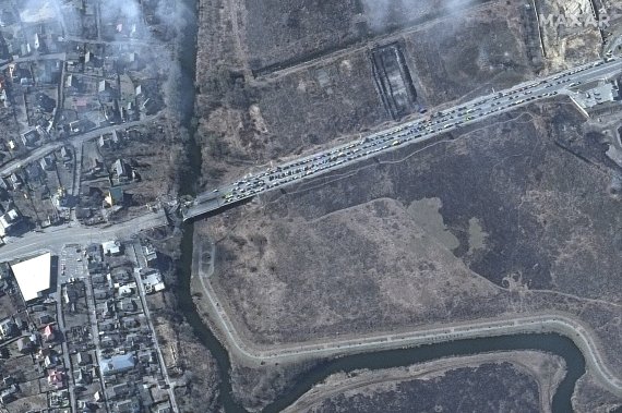 [이르핀=AP/뉴시스] 막사 테크놀로지스가 제공한 위성사진에 14일(현지시간) 우크라이나 이르핀의 파괴된 다리와 연결된 도로에 차량이 길게 밀려 있다. 2022.03.15.