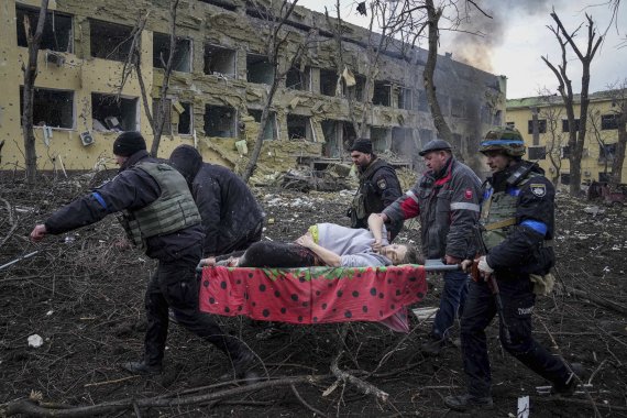 우크라이나 구급대원들과 자원봉사자들이 9일(현지시간) 러시아군의 포격을 받은 마리우폴 시내 중심가의 산부인과 병원에서 한 임산부를 들것에 실어 옮기고 있다. 미국은 23일 러시아가 우크라이나에서 전쟁범죄를 저지르고 있다고 공식 선언했다. AP뉴시스