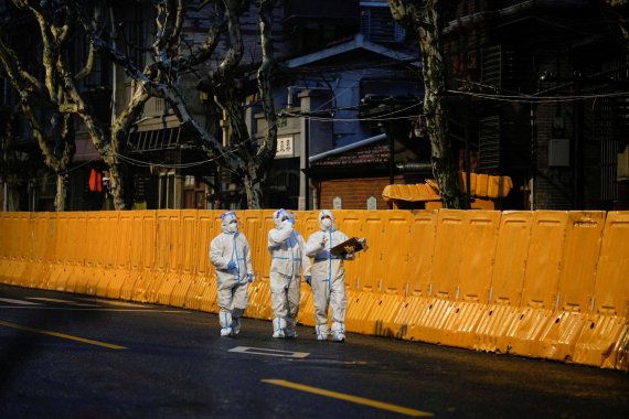 코로나19가 대유행인 중국 상하이에서 개인보호장비(PPE)를 착용한 의료진들이 봉쇄된 지역의 장벽 앞을 걷고 있다. © 로이터=뉴스1.사진=뉴스1