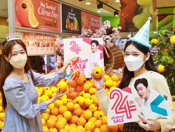 롯데마트 모델들이 서울역점에서 '오렌지 한망 가득 골라담기' 행사를 소개하고 있다.