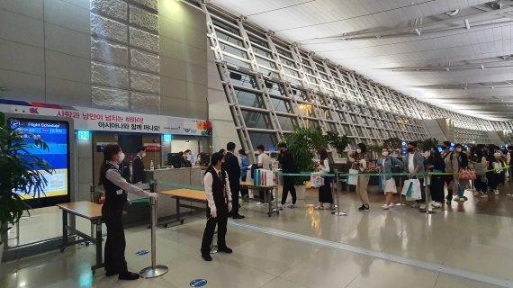 지난 3일 인천국제공항 제1여객터미널에서 아시아나항공 하와이(호놀룰루)행 항공편 탑승 여객들이 인천공항과 아시아나항공에서 준비한 운항 재개 기념품을 받으며 탑승을 준비하고 있다. (인천국제공항공사 제공) 2022.4.4/뉴스1