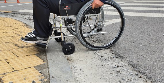 [부천=뉴시스] 정일형 기자 = 4일 경기 부천시의 한 횡단보도에서 휠체어를 탄 장애인이 편차 높이로 인해 보행에 불편을 겪고 있다. 2022.04.04 jih@newsis.com