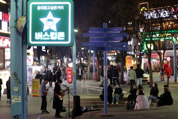 4일 오후 서울 마포구 홍대거리 버스킹존에서 시민들이 거리공연을 즐기고 있다. 중앙재난안전대책본부에 따르면 이날 0시부터 오는 17일까지 2주간 사적모임 가능 인원은 10명, 식당과 카페 등 다중이용시설 영업제한 시간은 밤 12시로 늘어난다. 행사나 집회 인원은 종전처럼 최대 299명까지로 유지된다. 정부는 위중증 환자·의료체계 여력 등이 안정적으로 유지된다면 2주 후에는 실내 마스크를 제외한 거리두기 해제도 가능하다는 입장이다. 2022.4.4/뉴스1 © News1 황기선 기자