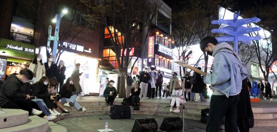 4일 오후 서울 마포구 홍대거리 버스킹존에서 시민들이 거리공연을 즐기고 있다. 중앙재난안전대책본부에 따르면 이날 0시부터 오는 17일까지 2주간 사적모임 가능 인원은 10명, 식당과 카페 등 다중이용시설 영업제한 시간은 밤 12시로 늘어난다. 행사나 집회 인원은 종전처럼 최대 299명까지로 유지된다. 정부는 위중증 환자·의료체계 여력 등이 안정적으로 유지된다면 2주 후에는 실내 마스크를 제외한 거리두기 해제도 가능하다는 입장이다. 2022.4.4/뉴스1 © News1 황기선 기자