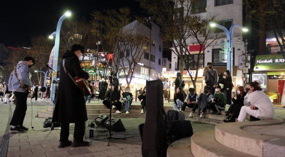 4일 오후 서울 마포구 홍대거리 버스킹존에서 시민들이 거리공연을 즐기고 있다. 중앙재난안전대책본부에 따르면 이날 0시부터 오는 17일까지 2주간 사적모임 가능 인원은 10명, 식당과 카페 등 다중이용시설 영업제한 시간은 밤 12시로 늘어난다. 행사나 집회 인원은 종전처럼 최대 299명까지로 유지된다. 정부는 위중증 환자·의료체계 여력 등이 안정적으로 유지된다면 2주 후에는 실내 마스크를 제외한 거리두기 해제도 가능하다는 입장이다. 2022.4.4/뉴스1 © News1 황기선 기자