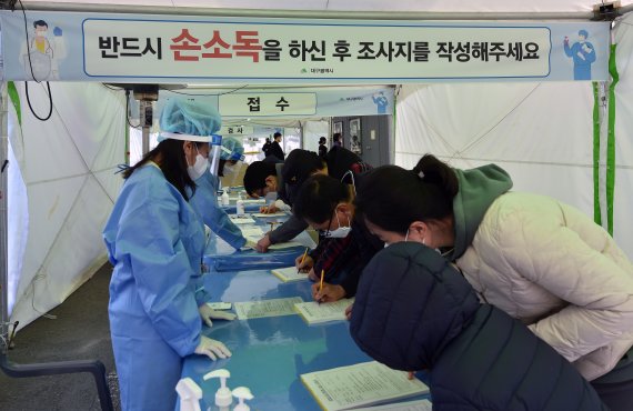 대구시 수성구 대구스타디움 제3주차장에 마련된 임시선별검사소에서 시민들이 코로나19 진단검사를 받기 위해 조사지를 작성하고 있다. 사진=뉴시스