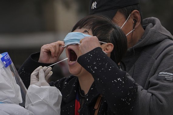 6일 중국 상하이의 코로나19 검사소에서 한 여성이 마스크를 들어 올린 채 코로나19 검사를 받고 있다. 2022.04.06 /사진=뉴시스