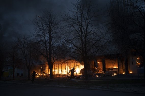 우크라이나 소방관들이 11일(현지시간) 러시아의 공격을 받아 불타고 있는 하르키우의 상점들 진화작업을 하고 있다. AP뉴시스