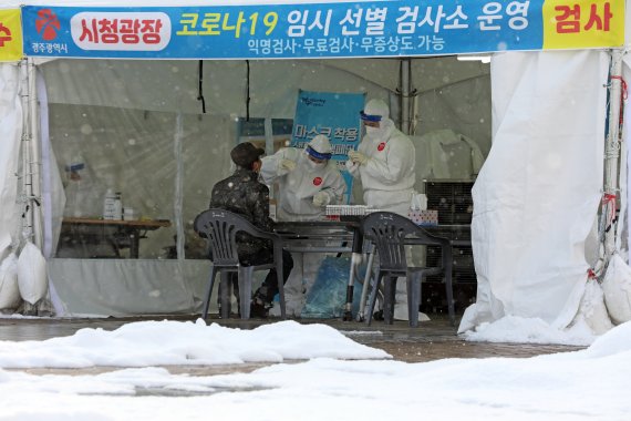 사흘동안 눈이 내리고 있는 31일 오후 광주시청 광장에 설치된 코로나19 임시 선별검사소에서 보건당국 관계자들이 시민들의 검체를 채취하고 있다. 2020.12.31/뉴스1 © News1 황희규 기자