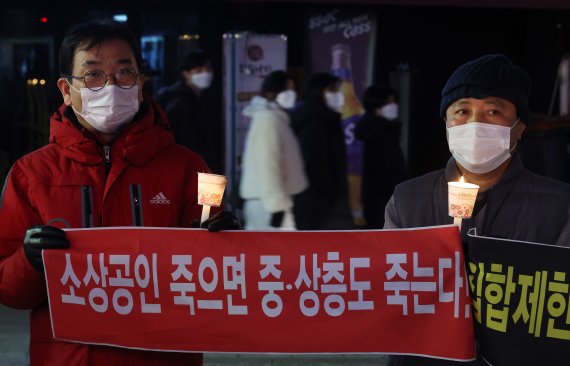 21일 오후 서울 마포구 홍대입구역 인근에서 정부의 영업시간 제한에 항의하는 촛불 문화 행사를 하는 코로나 피해 자영업 총연합 회원들 뒤로 10시가 지나 가게를 나온 시민들이 지나가고 있다. 이날 자영업자들은 밤 10시부터 영업시간 제한 철폐를 요구하는 점등시위를 이어갔다. 2022.2.21/뉴스1 © News1 조태형 기자