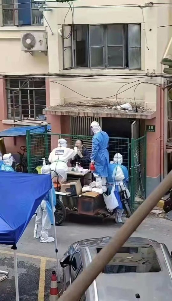 코로나19로 인해 격리된 중국 상하이 주민이 울타리를 사이에 두고 방역 당국 관계자로부터 PCR 검사를 받고 있다. 트위터 갈무리