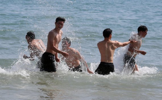 [부산=뉴시스] 하경민 기자 = 실외 마스크 착용 의무화 해제를 하루 앞둔 1일 부산 해운대해수욕장을 찾은 대학생들이 바다에 뛰어들어 물놀이를 즐기고 있다. 2022.05.01. yulnetphoto@newsis.com