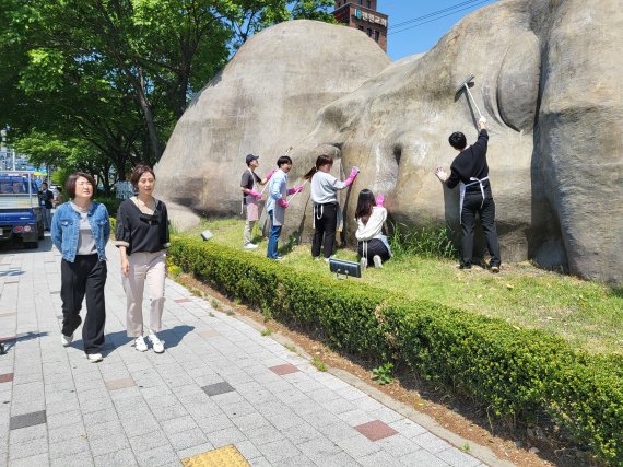 실외마스크 착용 의무 해제에 맞춰 대형 마스크를 벗은 거대원시인을 깨끗하게 정소하고 있다. 사진=달서구 제공