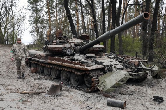 지난달 19일(현지시간) 한 우크라이나 군인이 수도 키이우 인근 지역에서 전투 후 버려진 러시아군 탱크 옆을 지나고 있다. 사진=뉴시스