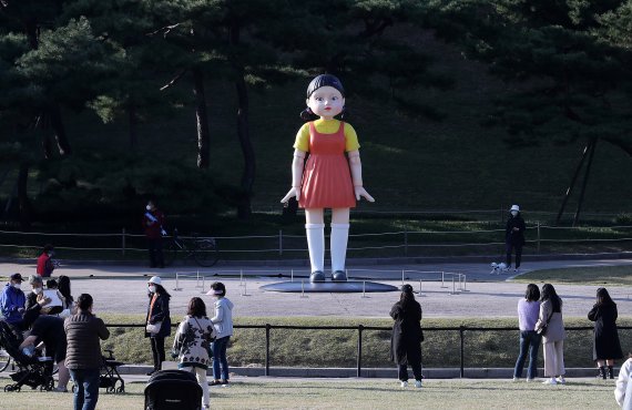 25일 오후 서울 송파구 올림픽공원 야외 88잔디마당에 설치된 넷플릭스 드라마 ‘오징어게임’ 영희 로봇 동상이 시민들 눈길을 끌고 있다. 올림픽공원은 “오늘부터 약 3개월간 영희 로봇 동상을 전시할 예정”이라고 밝혔다. 4m 높이의 영희 동상에서는 ‘오징어게임’ OST와 함께 ‘무궁화 꽃이 피었습니다’라는 드라마 속 음성도 나온다. 2021.10.25/뉴스1 © News1 박세연 기자