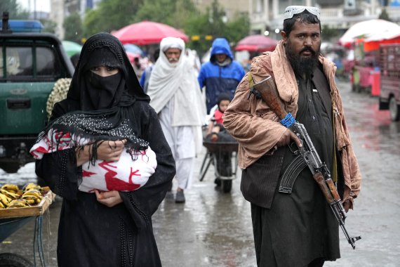 탈레반 무장대원이 순찰하는 가운데 아프가니스탄 수도 카불 도심을 7일(현지시간) 한 여성이 부르카를 쓰고 걷고 있다. 탈레반은 이날 모든 아프간 여성들은 공공장소에서 머리부터 발끝까지 가리는 부르카를 착용해야 한다고 명령했다. AP뉴시스
