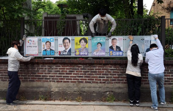 6·1 전국동시지방선거를 앞두고 19일부터 공식 선거운동에 돌입한 가운데 서울 종로구선거관리위원회 직원들이 서울 종로구 예술가의 집 울타리에 선거벽보를 게시하고 있다. 사진=박범준 기자