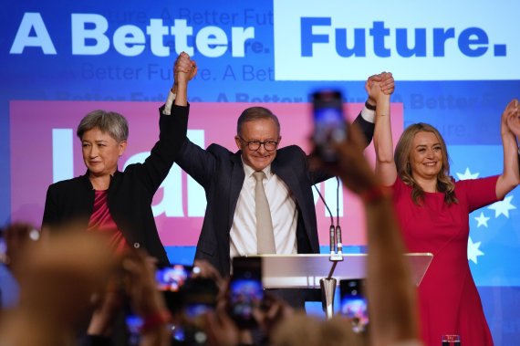 호주의 새 총리로 당선된 앤서니 알바니즈 노동당 대표(가운데)가 22일 호주 시드니에서 열린 노동당 집회에서 두 팔을 들고 당원들에게 총선 승리를 알리고 있다. AP뉴시스