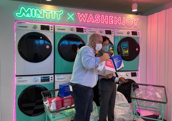 지난 24일 서울 마포구 민팃 팝업스토어 ‘민팃 폰 세탁소’에서 게리 스틸 테스 CEO(왼쪽)와 하성문 민팃 대표가 서비스를 체험하고 기념촬영을 하고 있다. SK에코플랜트 제공