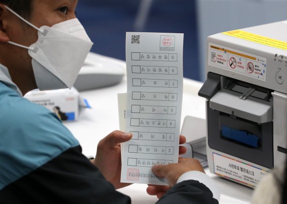 6·1 지방선거와 국회의원 보궐선거 사전투표일인 27일 오전 서울 구로구 궁동 청소년문화의집에 마련된 사전투표소에서 관계자가 유권자에게 투표용지를 건네고 있다. 2022.5.27/뉴스1 © News1 이동해 기자