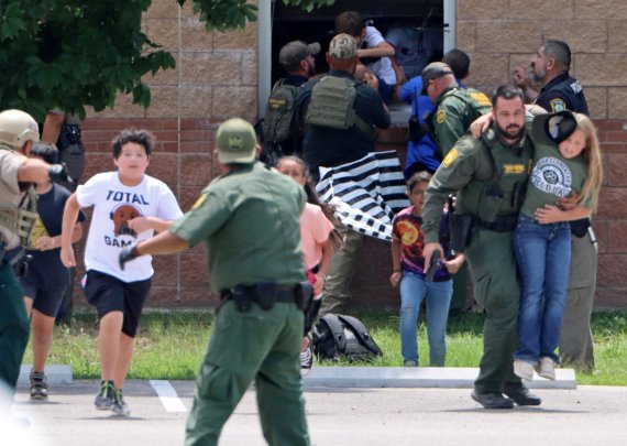 Children run to safety after escaping from a window during a mass shooting at Robb Elementary School where a gunman killed nineteen children and two adults in Uvalde, Texas, U.S. May 24, 2022. Picture taken May 24, 2022. Pete Luna/Uvalde Leader-News/Handout via REUTERS NO RESALES. NO ARCHIVES. MANDA