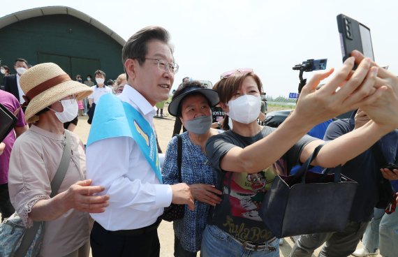 [인천=뉴시스] 국회사진기자단 = 이재명 더불어민주당 인천 계양을 국회의원 보궐선거 후보가 29일 인천 계양구 김포도시철도 기지창 인근에서 '지하철 9호선 계양 연장 공약'을 발표를 마친 후 지지자들과 기념촬영을 하고 있다. 2022.05.29. photo@newsis.com