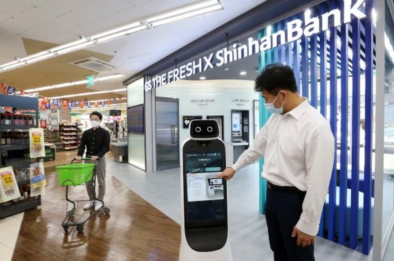 신한은행이 금융권 최초로 GS리테일과 선보인 서울 광진구 슈퍼마켓 혁신점포에서 고객이 로봇 컨시어지의 도움을 받고 있다. 사진=이병철기자