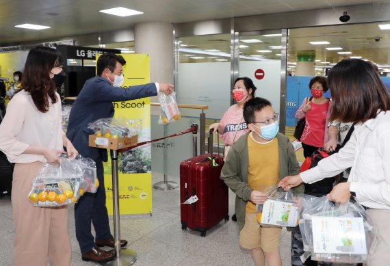 제주도와 제주관광공사 직원 등이 15일 오전 제주국제공항 국제선 도착장에서 스쿠트항공기 TR812 편 탑승객들에게 기념품을 나눠주고 있다. 싱가포르 창이국제공항에 출발한 스쿠트항공은 주 3회(수, 금, 일) 정기적으로 제주 노선을 운항한다. 무사증 재개 이후 국제선 정기 취항은 이번이 처음이다.2022.6.15/뉴스1 © News1 고동명 기자