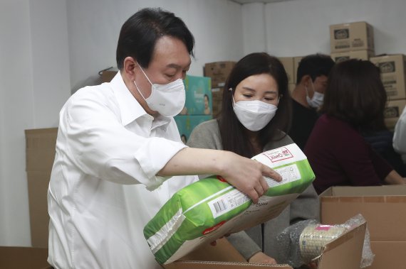 [서울=뉴시스] 국회사진기자단 = 윤석열 대통령이 대선 후보 시절 서울 성동구 가온한부모복지협의회를 방문해 한부모 가정에게 보낼 물품을 포장하고 있다. 2021.12.15. photo@newsis.com