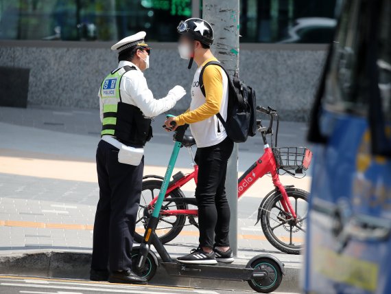 전동킥보드 등 개인형 이동장치(PM)의 이용 규제를 강화하는 개정 도로교통법 시행이 시작된 13일 오후 서울 마포구 홍대입구역 인근 인도에서 마포경찰서 경찰들이 전동킥보드를 이용하는 시민에게 재개정 관련 내용 홍보 및 계도를 하고 있다. © News1 김진환 기자
