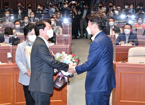 이준석 국민의힘 대표가 지난 14일 오후 서울 여의도 국회에서 열린 의원총회에서 안철수 의원에게 꽃다발을 전달하고 있다. (공동취재사진)