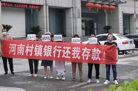 [서울=뉴시스] 23일 중국 산둥성 허저에서 몇명의 사람들이 '허난성 시골은행은 우리의 예금을 돌려달라'는 플래카드를 들고 시위를 벌이고 있다. <사진출처: 중국 웨이보> 2022.06.24