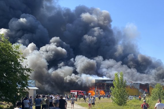 27일(현지시간) 우크라이나 크레멘추크에서 시민들이 러시아의 미사일 공격으로 연기가 솟구치는 쇼핑몰을 지켜보고 있다. 우크라이나 당국은 이번 공격으로 최소 13명이 숨지고 58명이 다쳤다고 밝혔다. 2022.06.28. /사진=뉴시스