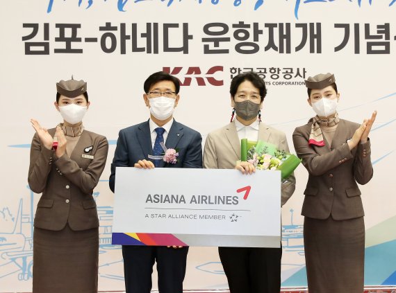 아시아나항공 정성권 대표(왼쪽 두번째)가 출발편 탑승객 1명에게 김포-하네다 노선 왕복 항공권을 증정한 뒤 기념촬영을 하고 있다. 아시아나항공 제공