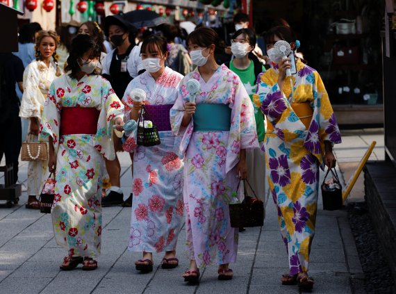 지난 29일 일본 도쿄의 대표적인 관광지인 아사쿠사에서 일본 전통복장인 기모노 차림의 여성들이 휴대용 미니 선풍기로 더위를 식히며 걷고 있다. 로이터 뉴스1