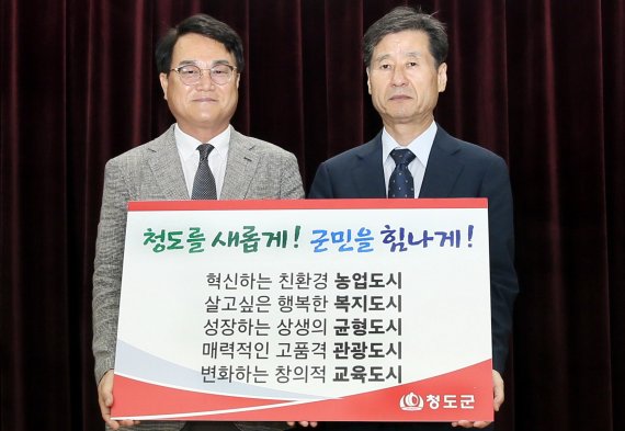 김하수 청도군수(왼쪽)이 박진우 청도군수직 인수위원장으로부터 시정 슬로건과 5대 군정방침을 전달받고 있다. (청도군 제공)2022.6.30/© 뉴스1