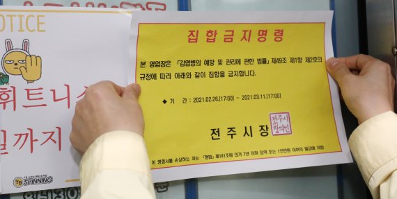 전북 전주시 TB휘트니스 효자점 발 신종 코로나바이러스 감염증(코로나19) 확진자가 집단 발생한 휘트니스장에 전주시 관계자가 집합금지명령을 붙이고 있다. 2021.2.26 © News1 유경석 기자