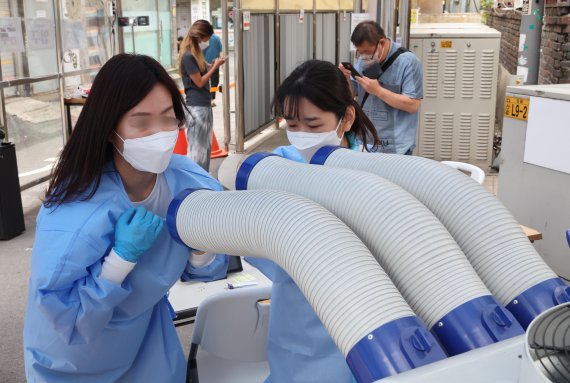 6일 서울 중구보건소 선별진료소에서 의료진이 냉풍기로 더위를 식히고 있다. 사진=박범준 기자