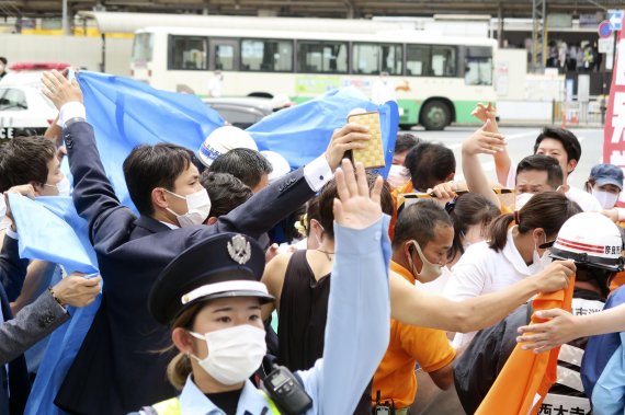 8일 일본 나라현 나라시에서 자민당 관계자들이 아베 신조 전 총리 총격 현장 주변을 둘러싸고 있다.AP뉴시스