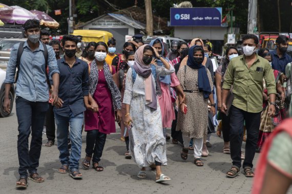 Job aspirants wearing face masks cross a street as they arrive for interviews organized by the state run employability center in Kochi, Kerala state, India, Friday, July 8, 2022. The southern state has made wearing masks mandatory in public places in the wake of rise in COVID-19 cases. (AP Photo/ R 