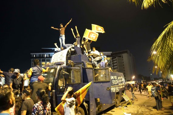 스리랑카 시민들이 9일(현지시간) 수도 콜롬보에서 경찰의 시위진압용 물대포를 점거한 뒤 환호하고 있다. AP뉴시스