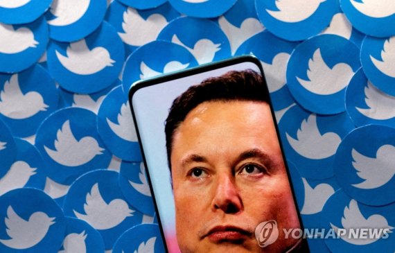 트위터 로고와 일론 머스크 테슬라 CEO FILE PHOTO: An image of Elon Musk is seen on smartphone placed on printed Twitter logos in this picture illustration taken April 28, 2022. REUTERS/Dado Ruvic/Illustration//File Photo