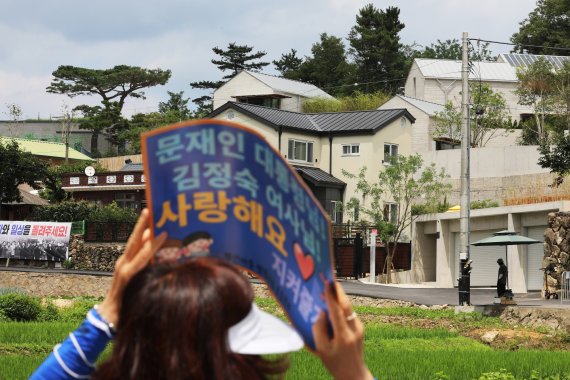 [양산=뉴시스] 차용현 기자 = 17일 오후 경남 양산시 하북면 평산마을 문재인 전 대통령 사저 앞에서 보수·진보 단체의 집회가 동시에 열린 가운데 한 진보단체 집회자가 문 전 대통령 내외를 지지하는 내용의 피켓을 들어보이고 있다. 2022.07.17. con@newsis.com